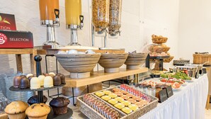 Ein reichhaltiges Buffet mit verschiedenen Speisen, darunter Gebäck, Obst und Getränke.