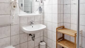 Ein modernes Badezimmer mit Waschbecken, Spiegel, Toilette und Duschbereich.