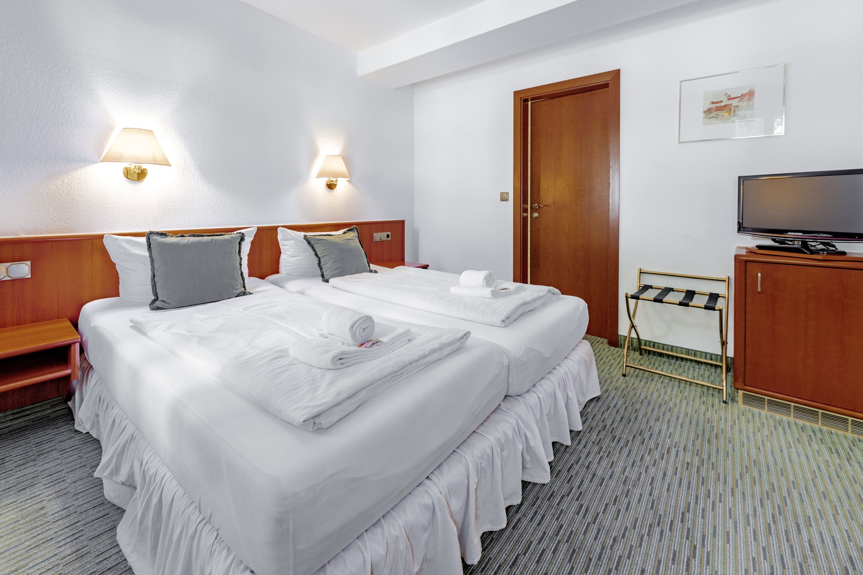 Een hotelkamer met twee bedden, een televisie, een bureau en een deur.