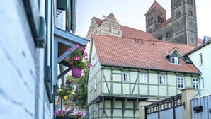 Eine Kopfsteinpflasterstraße mit traditionellen Fachwerkhäusern, einem Kirchturm und hängenden Blumenkörben.