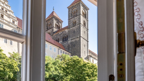 Blick auf ein historisches Gebäude mit einem markanten Turm und angrenzenden kleineren Gebäuden.