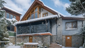 Un chalet con fachada de piedra, vigas de madera y un amplio ventanal.