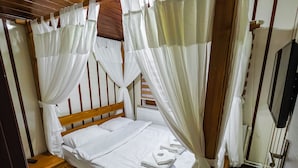 Una cama bien hecha con ropa blanca, un cabecero de madera y un dosel con cortinas blancas.
