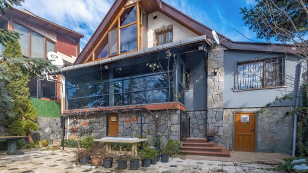 Una casa moderna con fachada de piedra, ventanas grandes y puerta de madera.