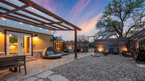 Un patio techado al aire libre con suelo de piedra, un banco de madera y una zona con fogón.