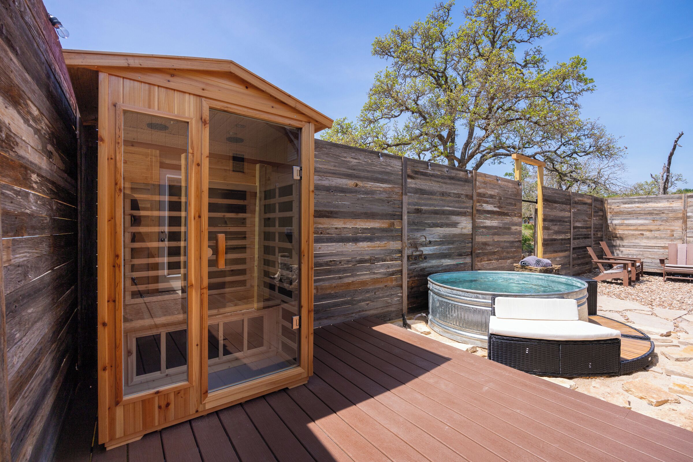 Una sauna de madera con puertas de vidrio, un jacuzzi y una terraza.