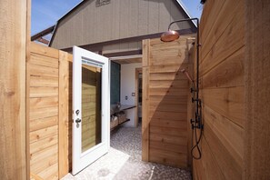 Fachada de madera con una puerta que da a un espacio exterior cubierto.