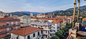 A residential area with multi-story buildings, balconies, and a mountainous backdrop. - Sea view 2 steps away from everything. 21A (Lavagna)