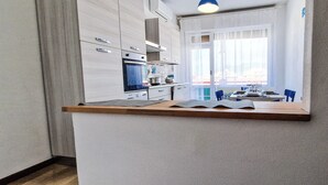 Une cuisine moderne avec des meubles blancs, un plan de travail en bois et un coin repas avec des chaises bleues.