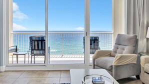 A balcony with a view of the ocean, a grey armchair, a small table, and a chair. - Majestic Beach Towers 1-1205 (Panama City Beach)