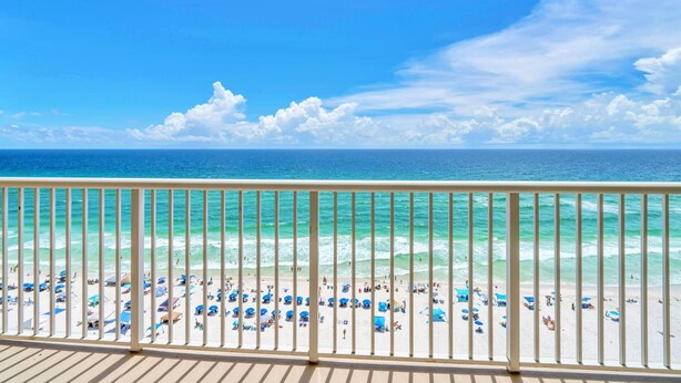 A beach view from a balcony with a railing, clear blue sky, and turquoise ocean. - Majestic Beach Towers 1-1205 (Panama City Beach)