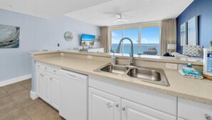 A kitchen with a large window, a sink, and cabinets. - Majestic Beach Towers 1-1205 (Panama City Beach)