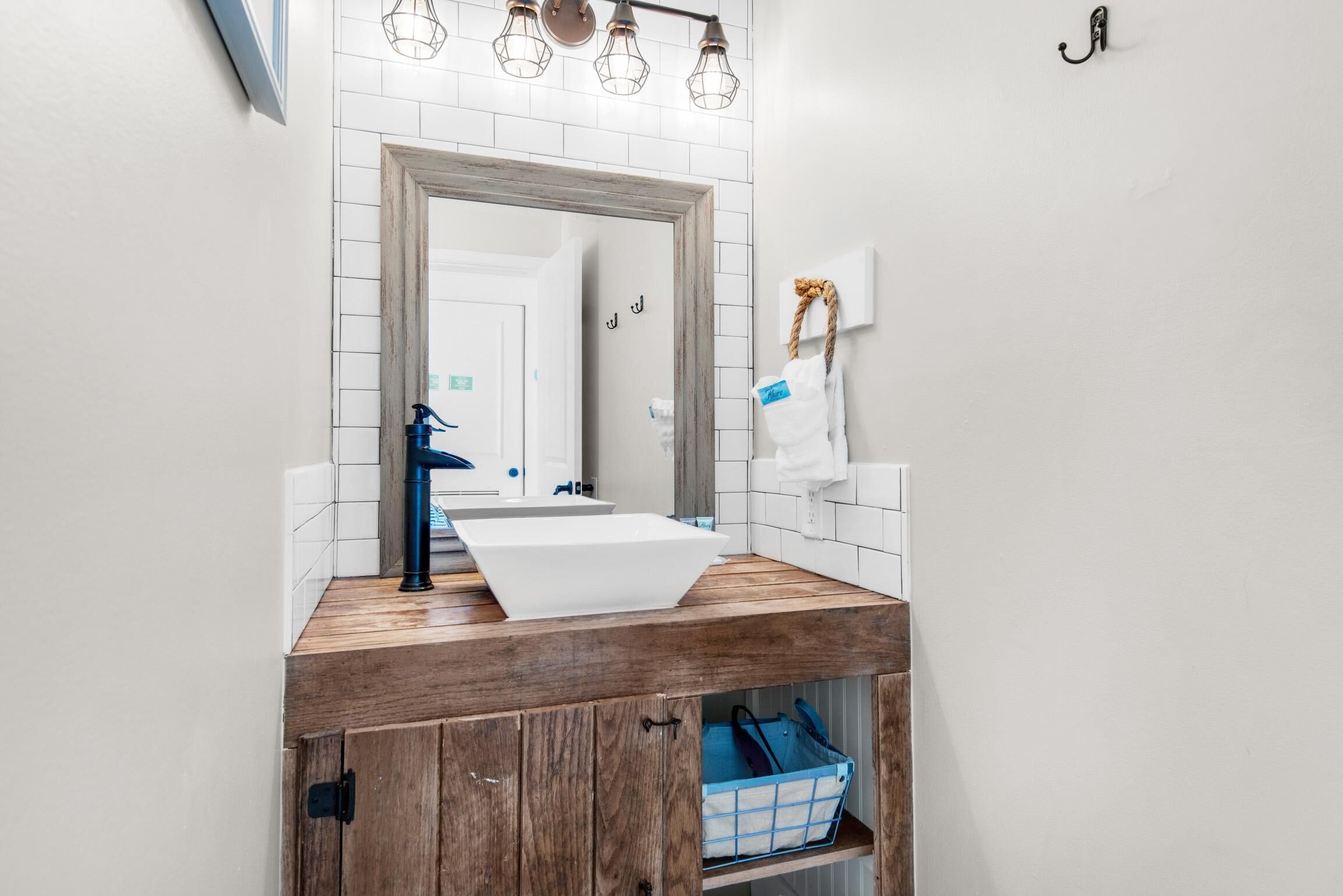 A bathroom with a wooden vanity, white sink, and a mirror with a wooden frame.
