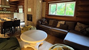 A cozy log cabin interior with a dining area, sofa, and a large window. - The Loghouse between Ghent and Bruges (Aalter)