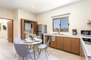 A modern kitchen with a dining area, equipped with a refrigerator, microwave, and a coffee maker.