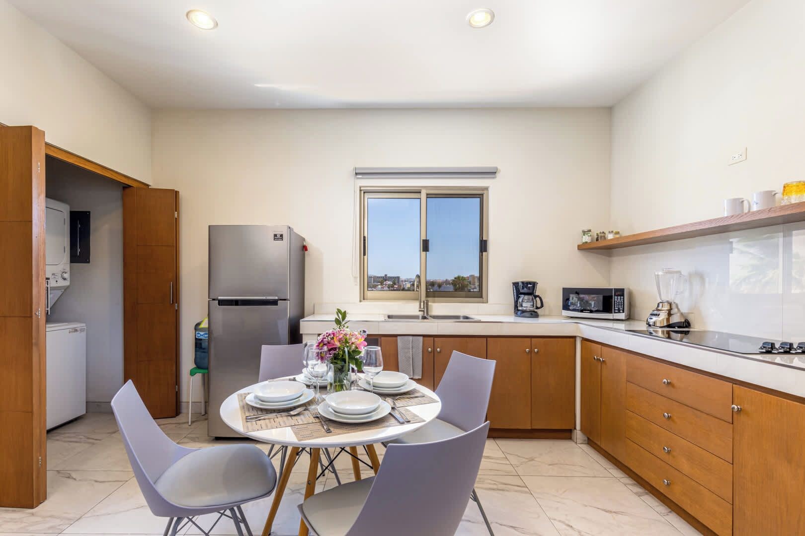 A compact kitchen with a dining area, a refrigerator, a microwave, and a window with a view.