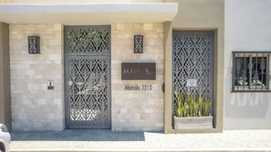 A building facade with two decorative metal gates, a sign indicating 'MAIA' and 'Abasolo 3510', and a small potted plant. - Centric Apt in Downtown - Rooftop Pool - Terrace (Cabo San Lucas)