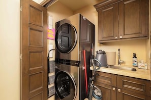 Une cuisine compacte équipée d’un lave-linge et d’un sèche-linge intégrés, d’une machine à café et d’un évier.