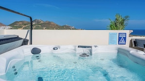 A hot tub with a clear view of the ocean and hills in the background.