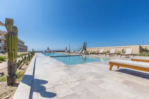 A pool area with lounge chairs and a cactus. - Luxury 2 BR Condo - Oceanview Pool - Gym (El Tezal)