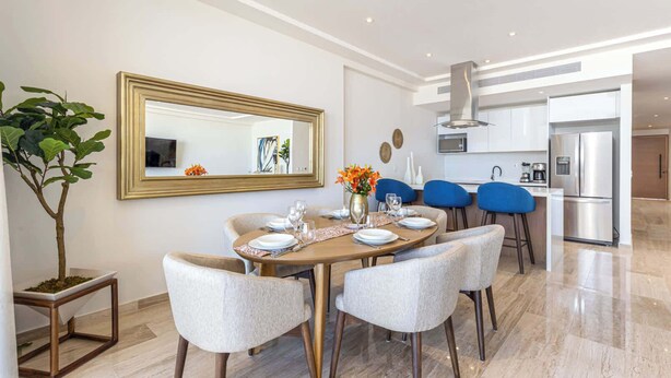 A modern dining area with a round table, six chairs, and a large mirror on the wall.