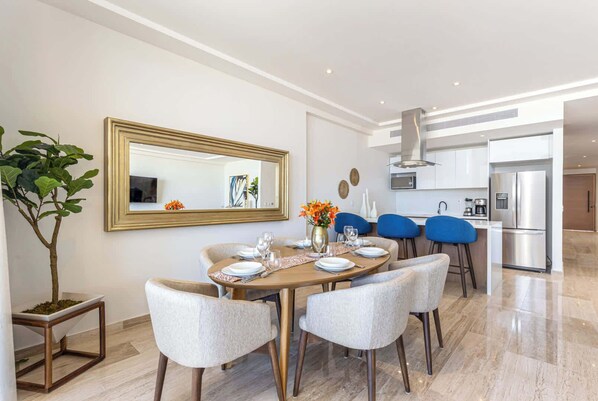 Un espace repas moderne avec une table ronde, six chaises et un grand miroir au mur.