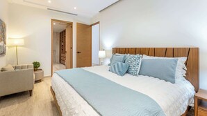 A bedroom with a bed, bedside tables, a chair, a lamp, and a wardrobe.
