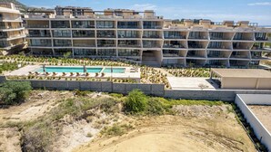 A modern multi-story residential building with a rooftop pool and sun loungers.