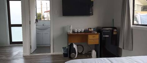 Ein Hotelzimmer mit Bett, Schreibtisch mit Computer, Fernseher und Minibar.