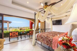 A bedroom with a bed, a TV, a ceiling fan, and a balcony with outdoor furniture.