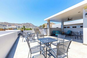 A rooftop terrace with outdoor seating, a pool, and a view of the city.
