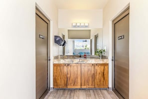 A bathroom with a wooden vanity, a mirror, a ceiling fan, and a view of the city through the window.