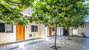 A courtyard with a tree, a yellow chair, a wooden door, and a staircase. - Centric Apt in Downtown - Rooftop Pool - Terrace (Cabo San Lucas)