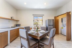 A modern kitchen with a dining table set for four, a refrigerator, microwave, and a washing machine.