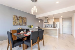 A modern kitchen with a central island, a dining area with a black table and chairs, and abstract art on the walls.