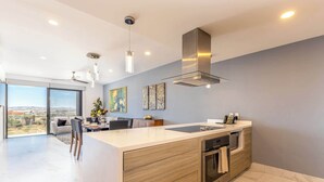 Een moderne keuken met een groot eiland, roestvrijstalen apparatuur en uitzicht op de omgeving.