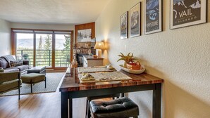 Una sala de estar con un ventanal grande, una mesa de comedor con individuales, un sofá y una mesa de centro.