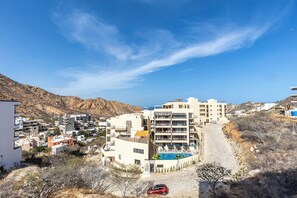 Un complejo turístico frente al mar con varias construcciones, una piscina y montañas al fondo.
