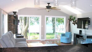 A spacious living room with a large window, a ceiling fan, and a fireplace.