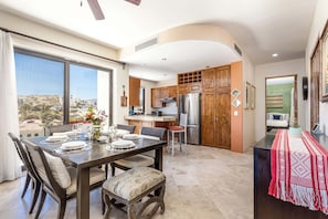Una cocina moderna con armarios de madera, un refrigerador de acero inoxidable y un comedor con una mesa dispuesta para cuatro.