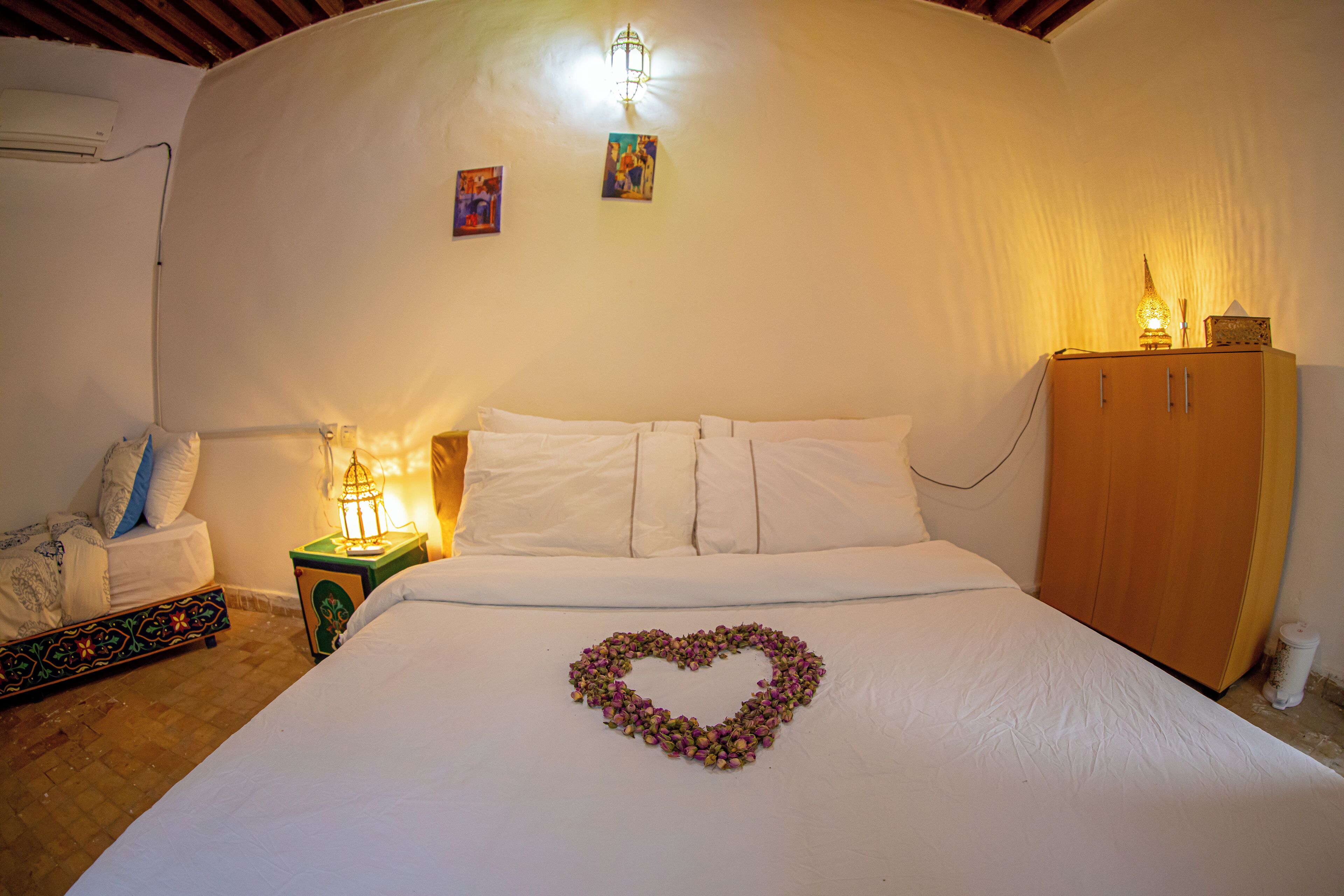 A bedroom with a bed, a nightstand, a cabinet, and a heart-shaped decoration on the bed.