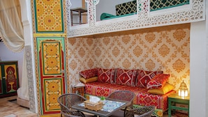 A cozy room with a patterned sofa, wicker chairs, a small table, and a decorative lantern. - RIAD MOHAMADIA (Fes)