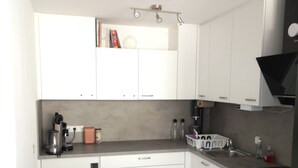 A compact kitchen with white cabinets, a built-in oven, and a coffee maker. - Apartment in Leonberg (close to Public Transport, City Park and Shopping Center) (Leonberg)