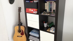 A room with a guitar, a bookshelf with books and decorative items, and a skateboard on the wall. - Apartment in Leonberg (close to Public Transport, City Park and Shopping Center) (Leonberg)