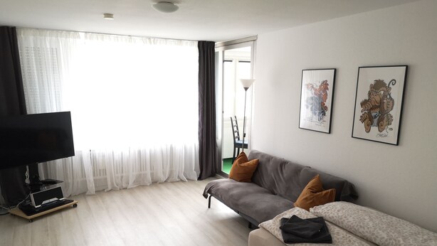 A modern living room with a grey sofa, a television, and artwork on the wall. - Apartment in Leonberg (close to Public Transport, City Park and Shopping Center) (Leonberg)