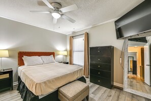 A bedroom with a bed, bedside tables, a ceiling fan, a wardrobe, and a mirror.