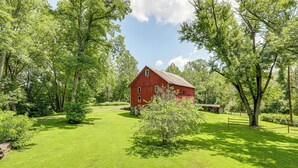 Une grange rouge, entourée d’arbres et d’herbe d’un vert luxuriant.