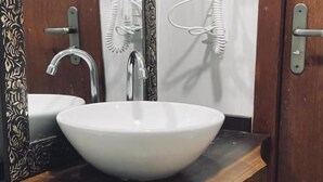 A bathroom with a white sink, a wooden vanity, a mirror with a floral design, and a towel rack. - Pousada Rosa Paradise (Imbituba)