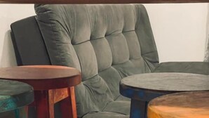 A room with a grey upholstered armchair and two wooden side tables. - Pousada Rosa Paradise (Imbituba)