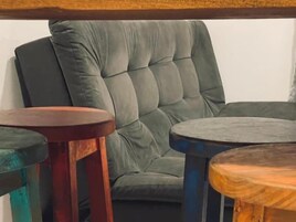 Una habitación con un sillón tapizado de color gris y dos mesitas de madera.